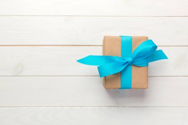Güzel hediye kutusu beyaz ahşap masa üzerinde mavi bir yay ile. üstten görünüm.