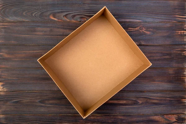 Open Cardboard box on a dark table, wooden background. top view.