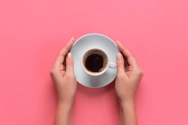 Kadın silah kupa kahve pembe bir arka plan üzerinde tutun. üstten görünüm ile cope yer.