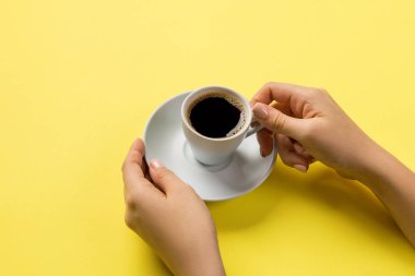 Bir fincan kahve sarı arka plan üzerinde tutan minimalist tarzı kadın el. Düz yatıyordu, en iyi görünümü.