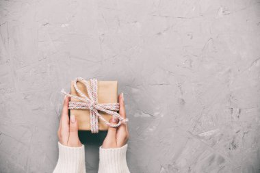 Kadın el kağıt kırmızı kurdele ile sarılmış Sevgililer veya diğer tatil el yapımı hediye vermek. Kutusu, dekorasyon hediye Beyaz Çimento rustik vintage tablo, kopya alanı ile üstten görünüm.