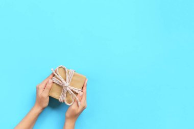 Hediye kutusu renk arka plan, üstten görünüm üzerinde pembe kurdele ile tutan kadın kolları.