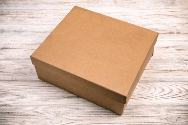 Kahverengi karton kutu ahşap arka plan üzerinde kapalı. üstten görünüm vintage, tonda, tasarım için boş.