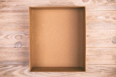 Ahşap zemin üzerine karton kutuyu açtın. Vintage, tonda üstten görünüm.