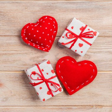 Sevgililer veya diğer tatil el yapımı mevcut kağıt ile tatil sarmalayıcı kırmızı kalpler ve hediye kutusunda. Tasarım için turuncu ahşap masa üstten görünüm kopya alanı ile boş alanı hediye kutusu.