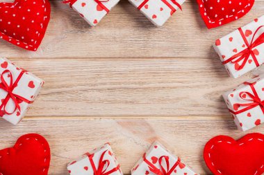 Sevgililer veya diğer tatil el yapımı mevcut kağıt ile tatil sarmalayıcı kırmızı kalpler ve hediye kutusunda. Tasarım için turuncu ahşap masa üstten görünüm kopya alanı ile boş alanı hediye kutusu.