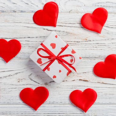 Sevgililer veya diğer tatil el yapımı mevcut kağıt ile tatil sarmalayıcı kırmızı kalpler ve hediye kutusunda. Tasarım için kopya alanı görünümüyle Beyaz ahşap masa üstü, boş alanı hediye kutusu.