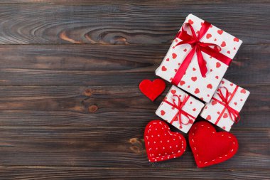 Sevgililer veya diğer tatil el yapımı mevcut kağıt ile tatil sarmalayıcı kırmızı kalpler ve hediye kutusunda. Tasarım için kopya alanı görünümüyle koyu ahşap masa üstü, boş alanı hediye kutusu.
