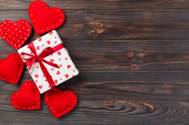 Sevgililer veya diğer tatil el yapımı mevcut kağıt ile tatil sarmalayıcı kırmızı kalpler ve hediye kutusunda. Tasarım için kopya alanı görünümüyle koyu ahşap masa üstü, boş alanı hediye kutusu.