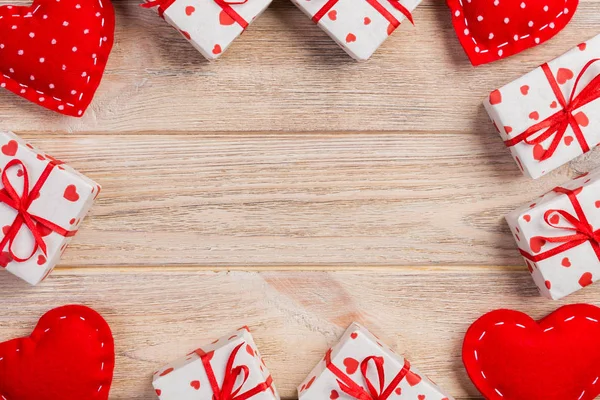 Sevgililer veya diğer tatil el yapımı mevcut kağıt ile tatil sarmalayıcı kırmızı kalpler ve hediye kutusunda. Tasarım için turuncu ahşap masa üstten görünüm kopya alanı ile boş alanı hediye kutusu.