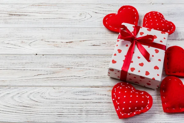 Sevgililer veya diğer tatil el yapımı mevcut kağıt ile tatil sarmalayıcı kırmızı kalpler ve hediye kutusunda. Tasarım için kopya alanı görünümüyle Beyaz ahşap masa üstü, boş alanı hediye kutusu.