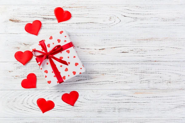 Sevgililer veya diğer tatil el yapımı mevcut kağıt ile tatil sarmalayıcı kırmızı kalpler ve hediye kutusunda. Tasarım için kopya alanı görünümüyle Beyaz ahşap masa üstü, boş alanı hediye kutusu.
