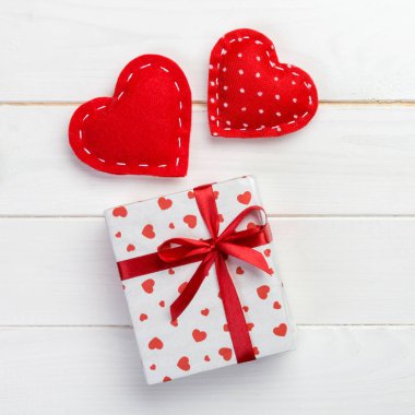 Sevgililer veya diğer tatil el yapımı mevcut kağıt ile tatil sarmalayıcı kırmızı kalpler ve hediye kutusunda. Tasarım için kopya alanı görünümüyle Beyaz ahşap masa üstü, boş alanı kutusu hediye sunmak.