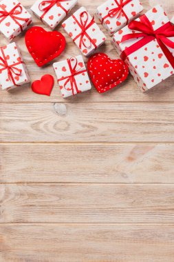 Sevgililer veya diğer tatil el yapımı mevcut kağıt ile tatil sarmalayıcı kırmızı kalpler ve hediye kutusunda. Tasarım için turuncu ahşap masa üstten görünüm kopya alanı ile boş alanı hediye kutusu.