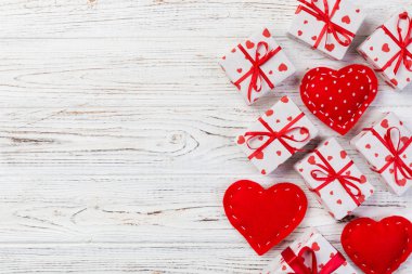Sevgililer veya diğer tatil el yapımı mevcut kağıt ile tatil sarmalayıcı kırmızı kalpler ve hediye kutusunda. Tasarım için kopya alanı görünümüyle Beyaz ahşap masa üstü, boş alanı hediye kutusu.