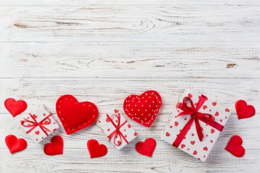 Sevgililer veya diğer tatil el yapımı mevcut kağıt ile tatil sarmalayıcı kırmızı kalpler ve hediye kutusunda. Tasarım için kopya alanı görünümüyle Beyaz ahşap masa üstü, boş alanı hediye kutusu.