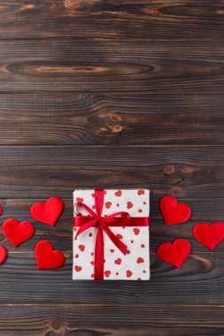 Sevgililer veya diğer tatil el yapımı mevcut kağıt ile tatil sarmalayıcı kırmızı kalpler ve hediye kutusunda. Tasarım için kopya alanı görünümüyle koyu ahşap masa üstü, boş alanı hediye kutusu.