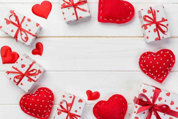 Sevgililer veya diğer tatil el yapımı mevcut kağıt ile tatil sarmalayıcı kırmızı kalpler ve hediye kutusunda. Tasarım için kopya alanı görünümüyle Beyaz ahşap masa üstü, boş alanı kutusu hediye sunmak.
