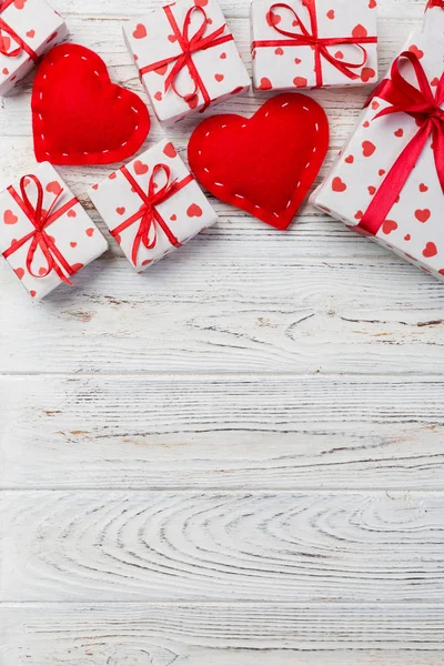 Sevgililer veya diğer tatil el yapımı mevcut kağıt ile tatil sarmalayıcı kırmızı kalpler ve hediye kutusunda. Tasarım için kopya alanı görünümüyle Beyaz ahşap masa üstü, boş alanı hediye kutusu.