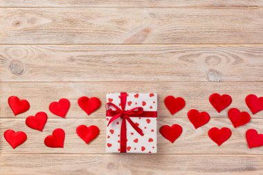 Sevgililer veya diğer tatil el yapımı mevcut kağıt ile tatil sarmalayıcı kırmızı kalpler ve hediye kutusunda. Tasarım için turuncu ahşap masa üstten görünüm kopya alanı ile boş alanı hediye kutusu.