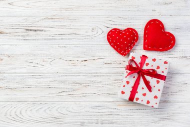 Sevgililer veya diğer tatil el yapımı mevcut kağıt ile tatil sarmalayıcı kırmızı kalpler ve hediye kutusunda. Tasarım için kopya alanı görünümüyle Beyaz ahşap masa üstü, boş alanı hediye kutusu.