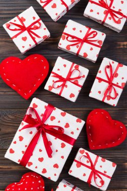 Sevgililer veya diğer tatil el yapımı mevcut kağıt ile tatil sarmalayıcı kırmızı kalpler ve hediye kutusunda. Tasarım için kopya alanı görünümüyle koyu ahşap masa üstü, boş alanı hediye kutusu.