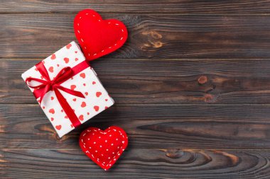 Sevgililer veya diğer tatil el yapımı mevcut kağıt ile tatil sarmalayıcı kırmızı kalpler ve hediye kutusunda. Tasarım için kopya alanı görünümüyle koyu ahşap masa üstü, boş alanı hediye kutusu.