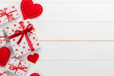Sevgililer veya diğer tatil el yapımı mevcut kağıt ile tatil sarmalayıcı kırmızı kalpler ve hediye kutusunda. Tasarım için kopya alanı görünümüyle Beyaz ahşap masa üstü, boş alanı kutusu hediye sunmak.