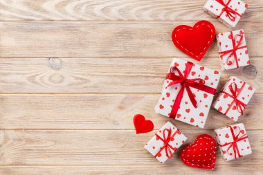 Sevgililer veya diğer tatil el yapımı mevcut kağıt ile tatil sarmalayıcı kırmızı kalpler ve hediye kutusunda. Tasarım için turuncu ahşap masa üstten görünüm kopya alanı ile boş alanı hediye kutusu.