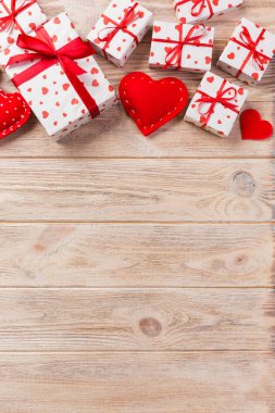 Sevgililer veya diğer tatil el yapımı mevcut kağıt ile tatil sarmalayıcı kırmızı kalpler ve hediye kutusunda. Tasarım için turuncu ahşap masa üstten görünüm kopya alanı ile boş alanı hediye kutusu.