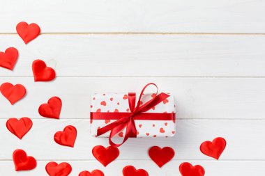 Sevgililer veya diğer tatil el yapımı mevcut kağıt ile tatil sarmalayıcı kırmızı kalpler ve hediye kutusunda. Tasarım için kopya alanı görünümüyle Beyaz ahşap masa üstü, boş alanı kutusu hediye sunmak.