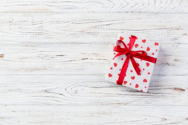 Sevgililer veya diğer tatil el yapımı mevcut kağıt ile tatil sarmalayıcı kırmızı kalpler ve hediye kutusunda. Tasarım için kopya alanı görünümüyle Beyaz ahşap masa üstü, boş alanı hediye kutusu.