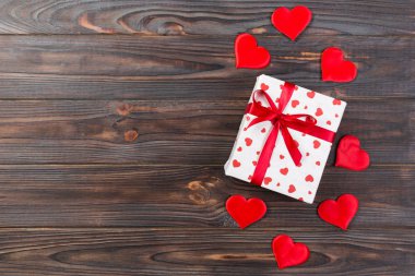 Sevgililer veya diğer tatil el yapımı mevcut kağıt ile tatil sarmalayıcı kırmızı kalpler ve hediye kutusunda. Tasarım için kopya alanı görünümüyle koyu ahşap masa üstü, boş alanı hediye kutusu.