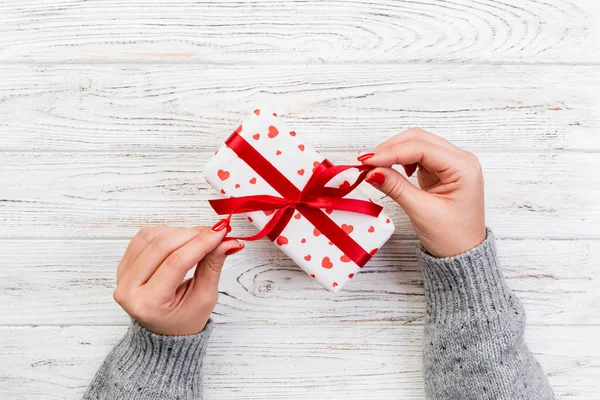 妇女的手给包装的情人节或其他节日手工礼物的纸与红色丝带 礼品桌上的礼物 礼品的红色心装饰 顶部视图与复制空间为您设计 — 图库照片