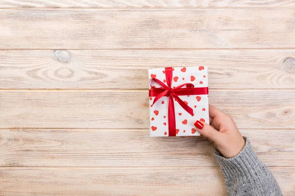 妇女的手给包装的情人节或其他节日手工礼物的纸与红色丝带 礼品桌上的礼物 礼品的红色心装饰 顶部视图与复制空间为您设计 — 图库照片