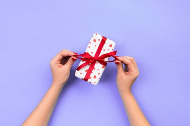 Kadın el kağıt kırmızı kurdele ile sarılmış Sevgililer veya diğer tatil el yapımı hediye vermek. Kopya alanı tasarım için hediye menekşe masada, üstten görünüm kutusunda, kırmızı kalp dekorasyon avantajlarıyla.