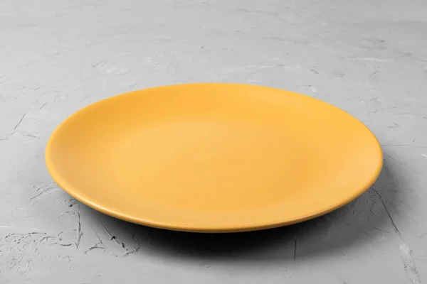 Top view of matte round empty orange plate on dark cement background copy space for you design. Perspective view.