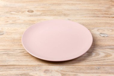 Perspektif görünümü. Turuncu ahşap arka plan akşam yemeği için boş gül mat çanak.