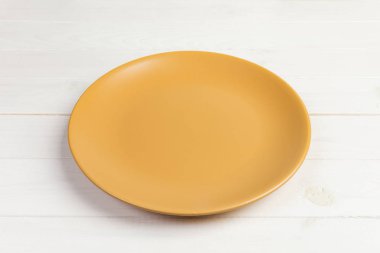 Perspektif görünümü. Akşam yemeği beyaz ahşap zemin için boş portakal mat çanak.