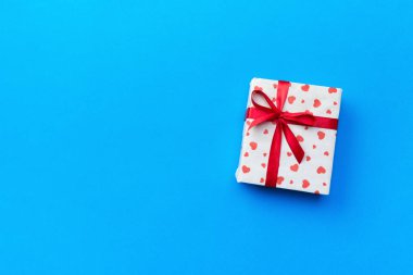 Hediye kutusu ile mavi arka plan üzerinde kırmızı kalpler. kopya alanı ile üstten görünüm.