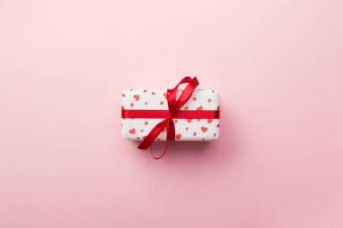 Sevgililer veya diğer tatil el yapımı mevcut kağıt ile tatil sarmalayıcı kırmızı kalpler ve hediye kutusunda. Tasarım için kopya alanı görünümüyle pembe renkli masa üstü, boş alanı hediye kutusu.