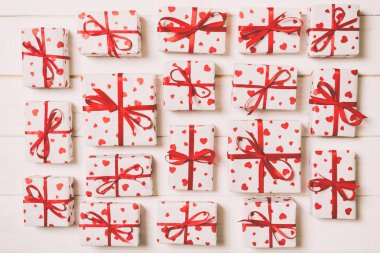 Kırmızı kurdeleli ve kalbi olan bir sürü hediye kutusu. Sevgililer Günü ya da diğer tatil kavramları. Ahşap arkaplanda en üstteki görünüm.