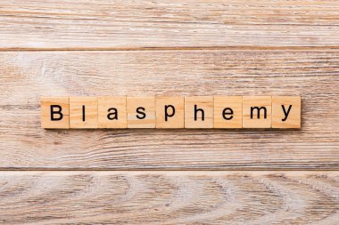 BLASPHEMY word written on wood block. BLASPHEMY text on wooden table for your desing, concept. clipart