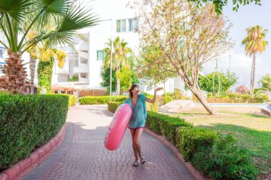 Muhteşem bir kadın telefon kulaklık müzik dinlemek, gülen ve dans şişme bir daire ile plaja gidiyor.