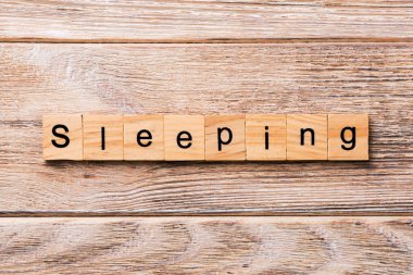 Ahşap blok üzerinde yazılı kelime uyuyor. Metin için tasarım, ahşap masa üzerinde uyku kavramı.