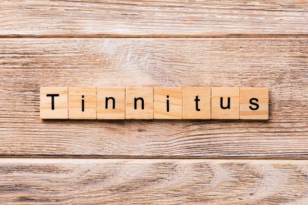 Kulak çınlaması kelime ahşap blok üzerinde yazılı. Kulak çınlaması metin, tasarım, ahşap masanın kavramı.