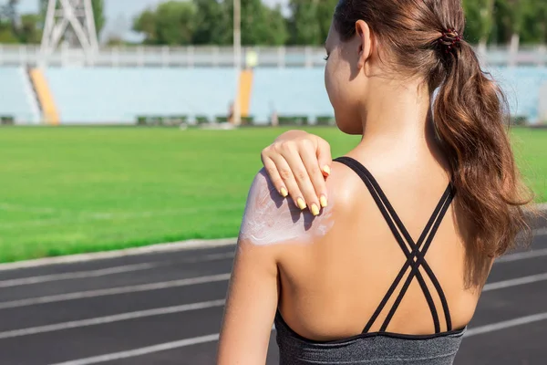 Ayakta ve güneş losyonu el koyarak genç kadın atlet. Sunscream egzersiz yaz sabahı çalışan spor önce kullanan kız. Spor ve sağlıklı kavramı.