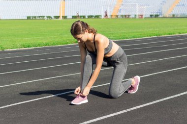 Genç kadın eller tarihinde bir stadyum, spor ve fitness kavramı çalıştırmak için hazır onun pembe spor ayakkabı bağcıklarımı bağla.