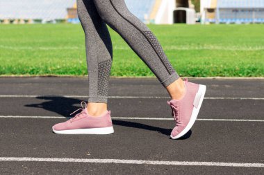 Bir koşu parkuru stadyum standları ile duran pembe spor ayakkabı kız bacaklar. Spor ve sağlıklı kavramı.