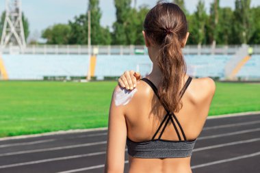 Güneş koruyucu güneş kremi. Güneş kremi güzel yaz günü omzuna koyarak bir spor giyim kadın. Sportif kadın spor stadyum üzerinde güneş koruyucu uygulanıyor. Spor ve sağlıklı kavramı.